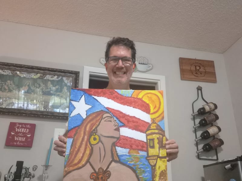Joelo mostrando una pintura con elementos de la cultura puertorriqueña